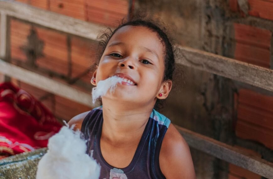Child eating cotton candy and smiling outdoors