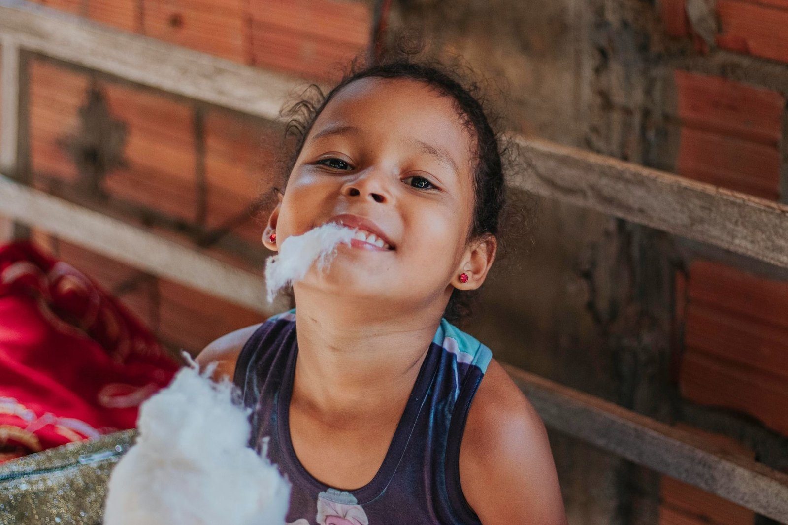 Child eating cotton candy and smiling outdoors